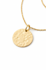 Close-up pendant detail of circular gold disc with hammered texture on Golden Aura Necklace