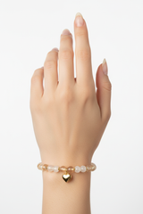 Elegant female hand wearing Heart Soul Bracelet with champagne moonstone beads and gold double heart charm