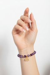Elegant female hand wearing Inner Peace Bracelet with lavender amethyst beads and gold charm