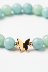 Jewelry macro close-up of Serenity Love Bracelet showing aquamarine bead texture and gold butterfly charm detail
