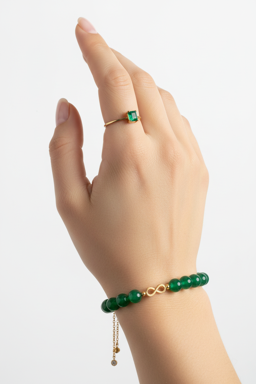 Elegant female hand wearing Harmony Stone Bracelet with jade green beads and gold infinity charm