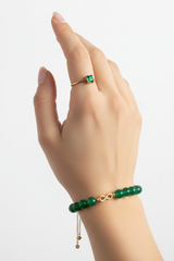 Elegant female hand wearing Harmony Stone Bracelet with jade green beads and gold infinity charm