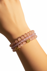 Elegant female hand wearing Pure Love Bracelet with blush pink and lavender crystal beads in warm sunlight