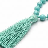 Close-up of mint green tassel on aqua blue turquoise mala necklace