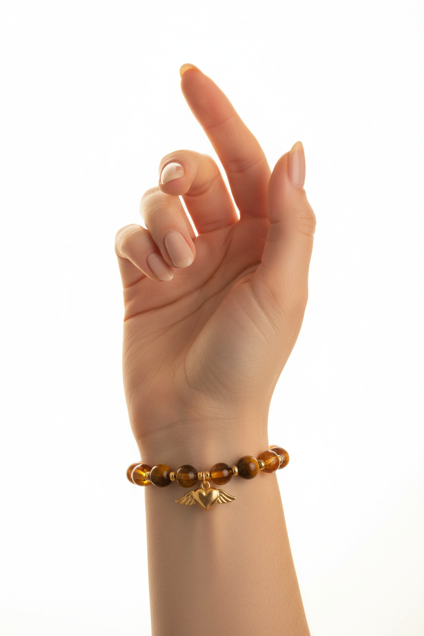Elegant female hand wearing Golden Love Bracelet with tiger's eye and amber beads and gold winged heart charm