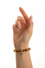 Elegant female hand wearing Golden Love Bracelet with tiger's eye and amber beads and gold winged heart charm