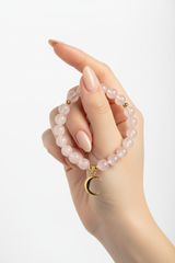 Elegant female hand wearing Calm Soul Bracelet with rose quartz beads and gold charm