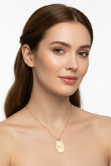 Elegant female model wearing Sacred Light Necklace with oval gold pendant and fine chain
