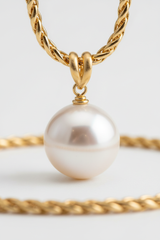 Macro detail of Le Pearl pearl pendant and polished gold chain craftsmanship