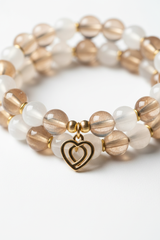 Jewelry macro close-up of Heart Soul Bracelet showing champagne moonstone bead shimmer and gold double heart charm