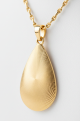 Macro close-up of teardrop gold pendant with sunray engraved lines on Divine Energy Necklace
