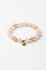Luxury feminine spiritual bracelet with pastel pink rose quartz and peach aventurine beads, diagonal angle view