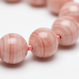 Macro close-up of blush rose gemstone beads on coral pink mala necklace